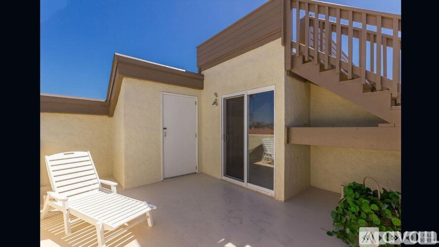 A white chair is placed on a patio.