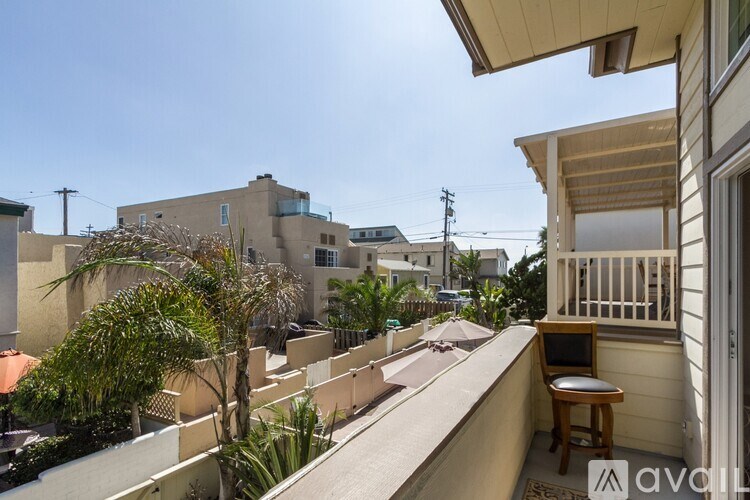 A balcony with a table and chairs overlooks a street with buildings.