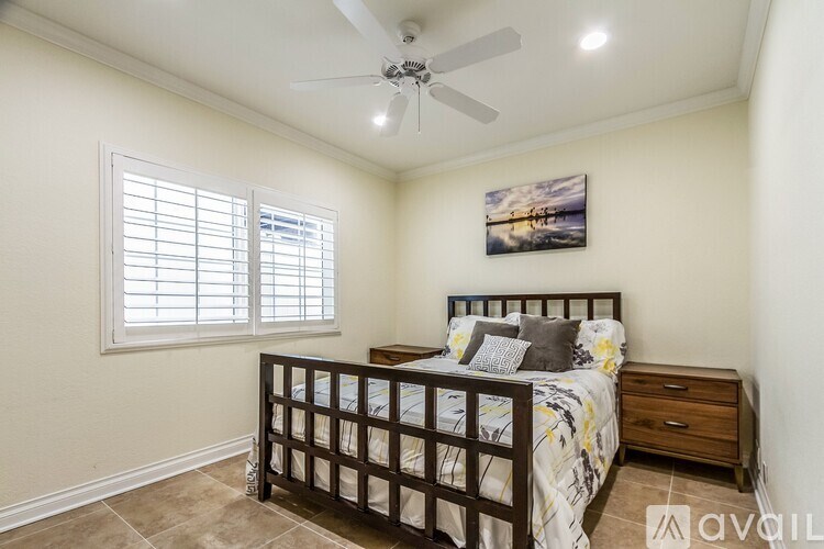 A bedroom with a bed, dresser, and a ceiling fan.