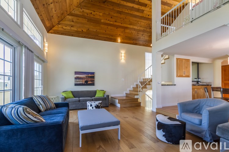 A living room with a blue couch and a wooden ceiling.