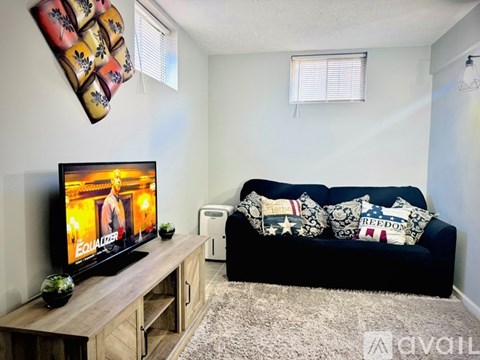 A living room with a black couch and a flat screen TV.