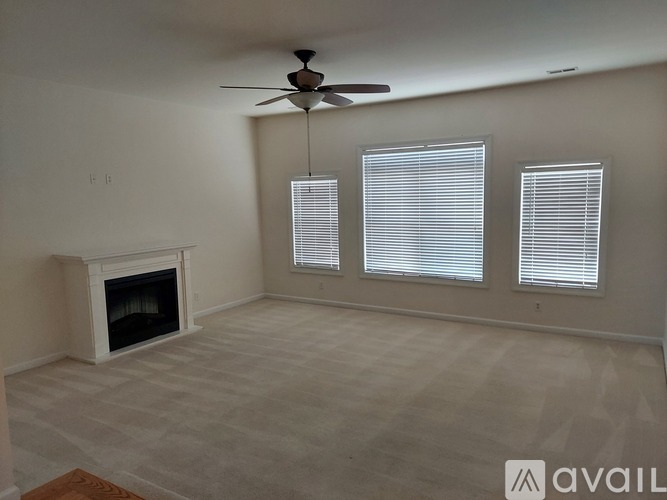 A living room with a fireplace and a ceiling fan.