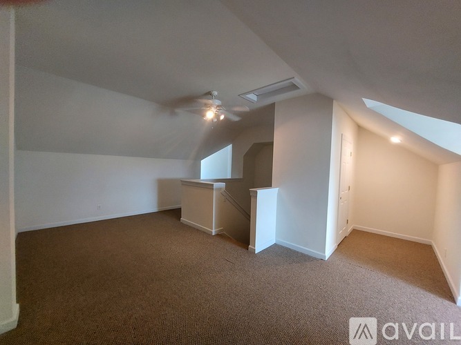 A spacious room with carpeted floor and a staircase leading to another room.