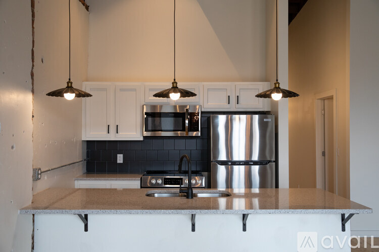A kitchen with a stainless steel refrigerator and a black and white backsplash.