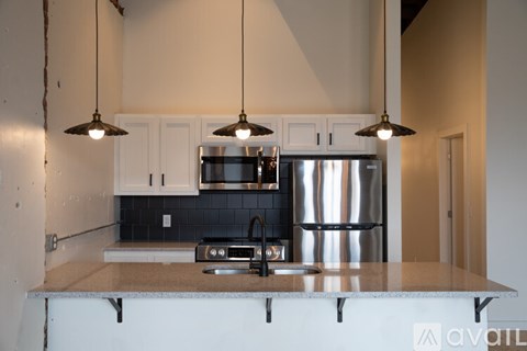 A kitchen with a stainless steel refrigerator and a black and white backsplash.