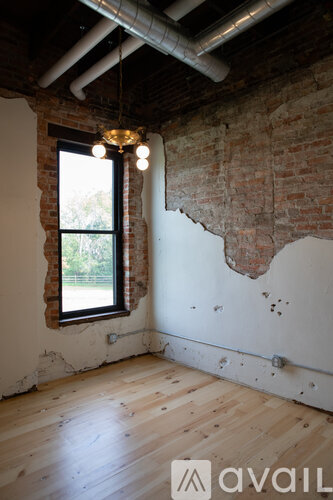 A room with a window and exposed brick walls.