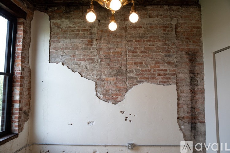 A room with a white wall and a brick wall with a chandelier hanging from the ceiling.