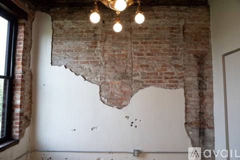 A room with a white wall and a brick wall with a chandelier hanging from the ceiling.