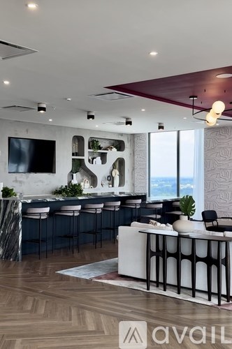 A modern bar area with a white counter and black chairs.