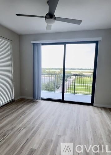 A room with a ceiling fan and sliding glass doors leading to a balcony.