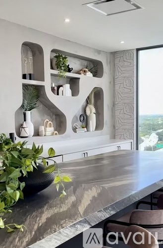 A modern kitchen with a marble countertop and a large window.