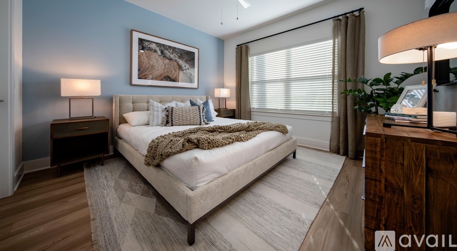 A bedroom with a large bed, a wooden floor, and a painting on the wall.