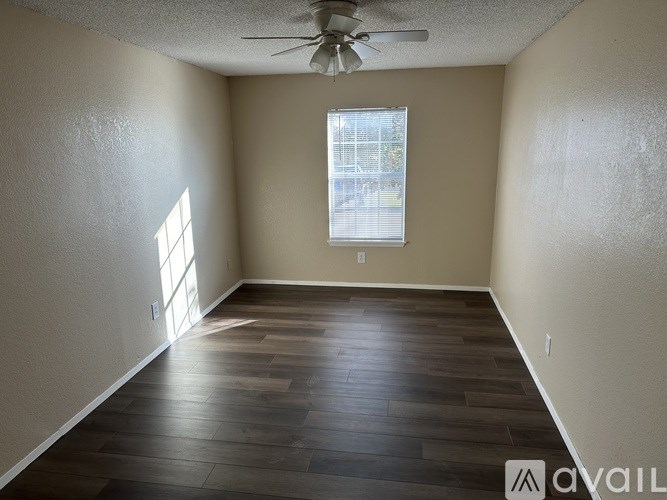 A room with a ceiling fan and a window with a view of a street.