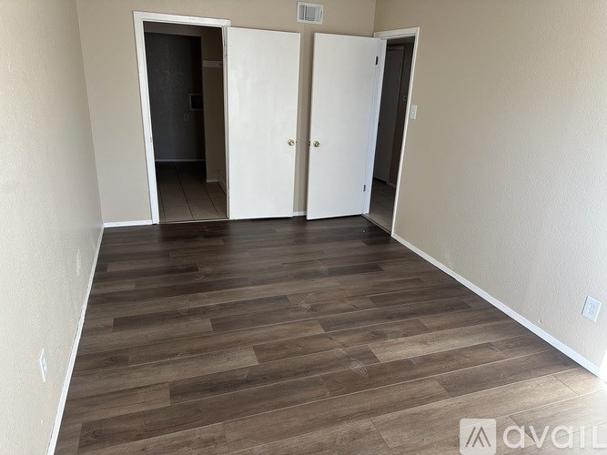 A room with a wooden floor and two white doors.