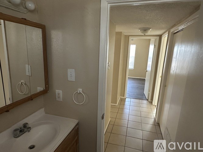 A bathroom with a sink, mirror, and toilet paper holder.