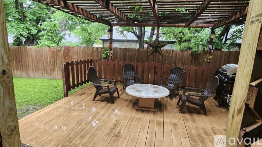 A wooden deck with a table and chairs under a roof.