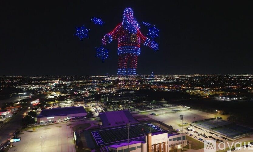 A large lighted figure of a person is projected onto a building at night.