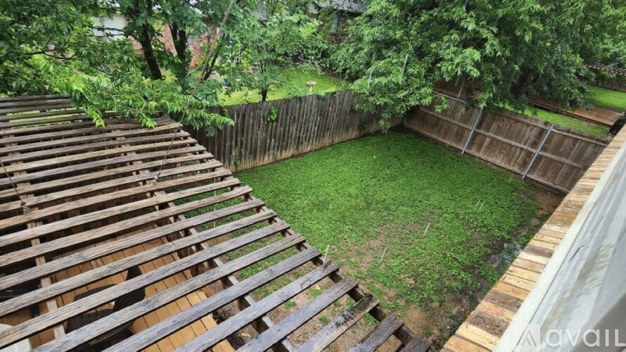 A backyard with a wooden deck and a fence.