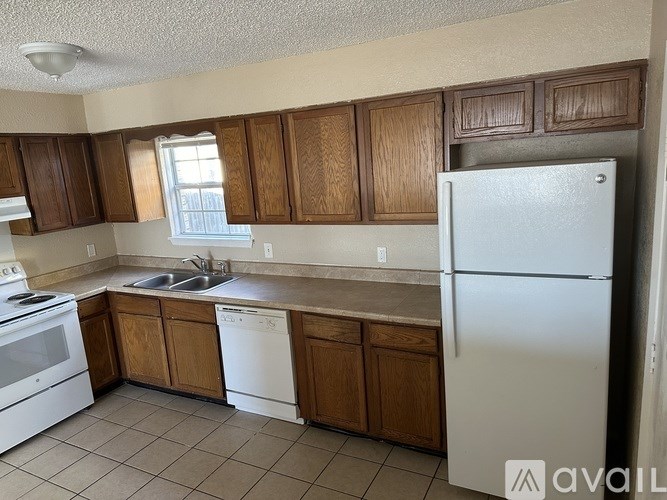 A kitchen with white appliances and wooden cabinets.