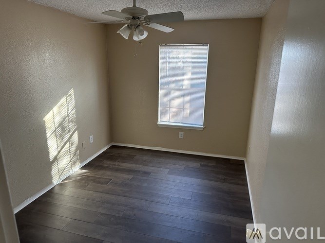 A room with a ceiling fan and a window with blinds.