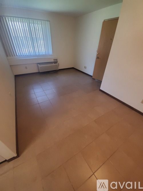 A room with wooden flooring and a window letting in sunlight.