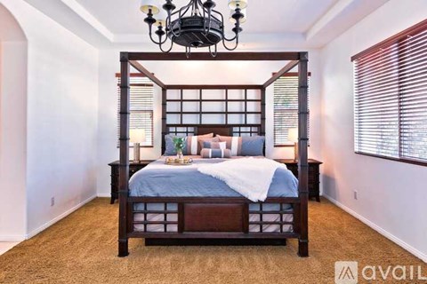 A bedroom with a four-poster bed and a chandelier.