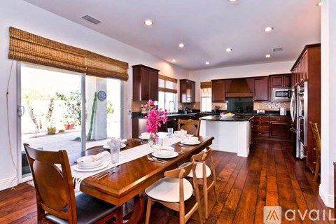 A kitchen with a table set for two with chairs around it.