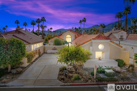 A house with a driveway and palm trees in the background.