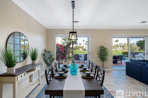 A dining room with a table set for six and a view of the backyard.