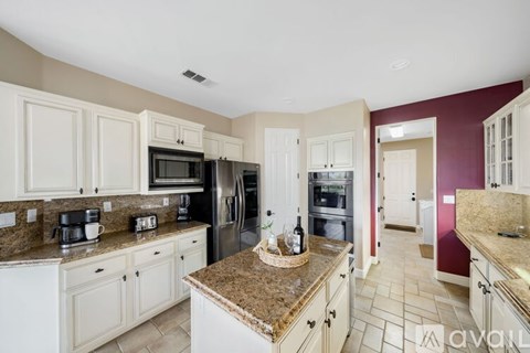 A kitchen with white cabinets and a granite countertop.