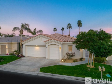 A house with a driveway and palm trees in front.