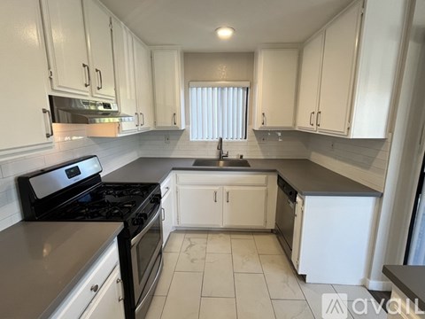 A kitchen with white cabinets and black appliances.