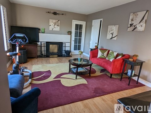 A living room with a red couch and a fireplace.