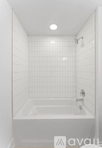 A white tiled bathroom with a white bathtub and shower.