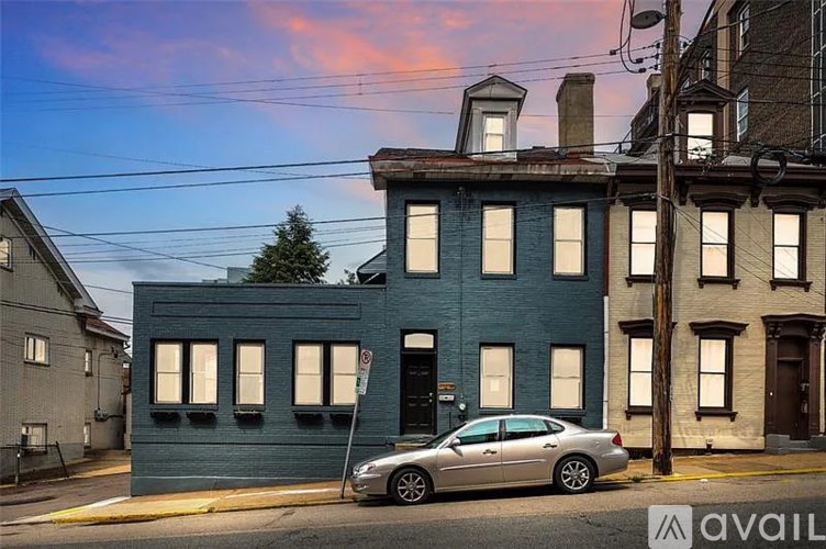 A silver car is parked in front of a blue building.