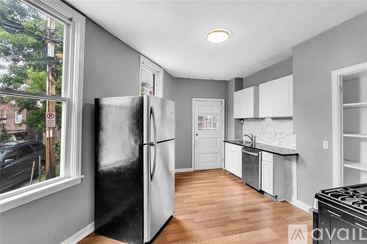 A kitchen with a black fridge and wooden floors.