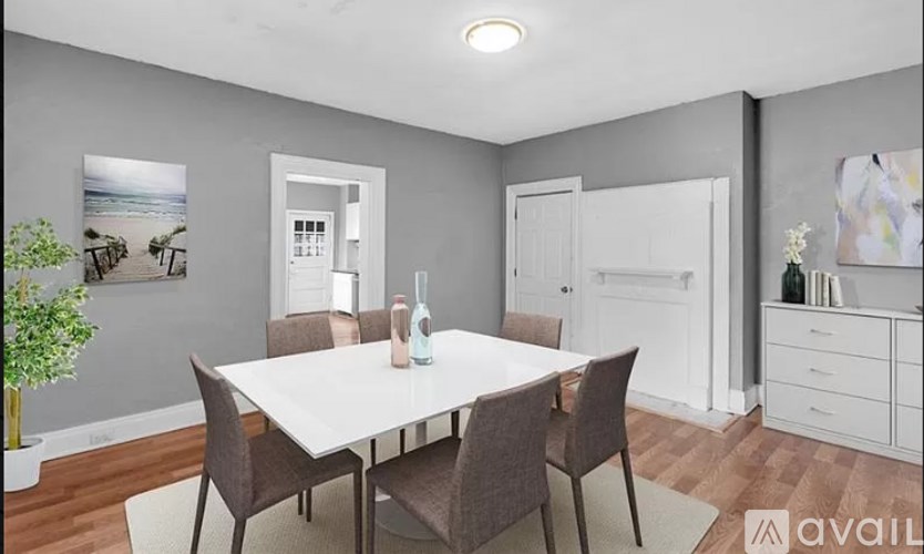A dining room with a white table and brown chairs.