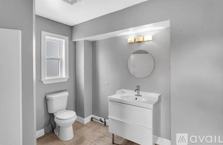 A bathroom with a toilet, sink, and mirror.