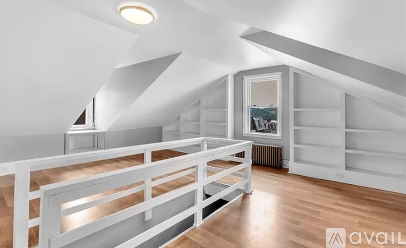 A white attic room with wooden floors and a skylight.