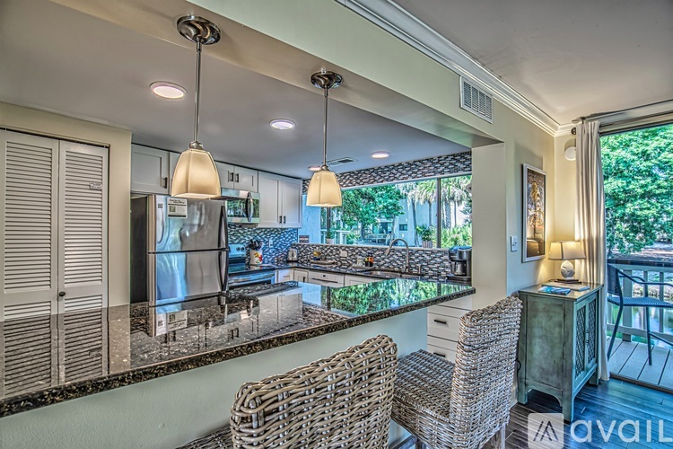 A kitchen with a refrigerator, sink, and a dining table with chairs.