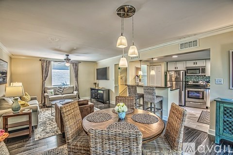 A living room with a brown wicker table surrounded by chairs.