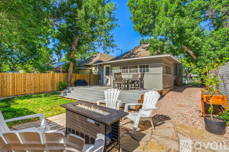 A backyard with a hot tub, chairs, and a house in the background.