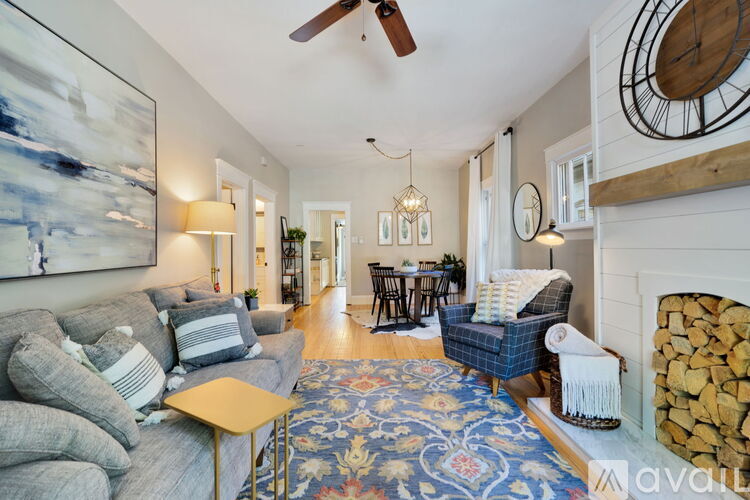 A living room with a grey couch and a blue and red rug.