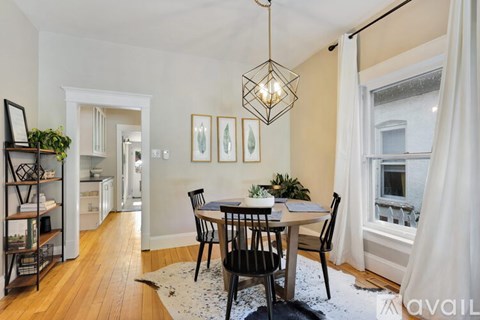 A dining room with a table set for four and a chandelier hanging from the ceiling.