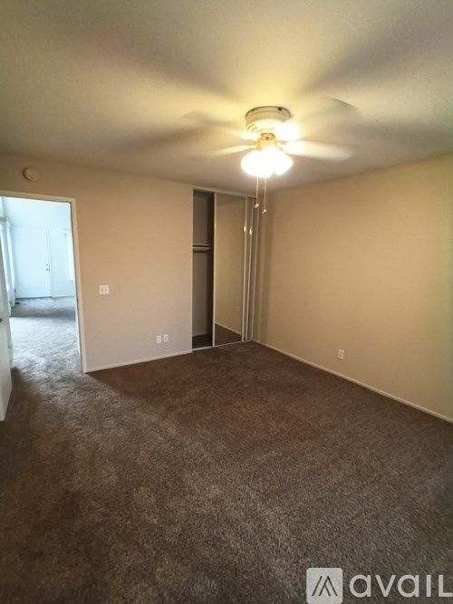 A room with a carpeted floor and a ceiling fan.