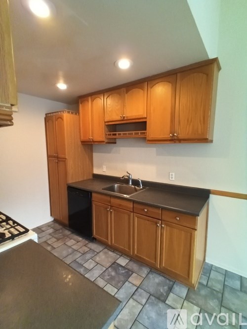 A kitchen with wooden cabinets and a black countertop.