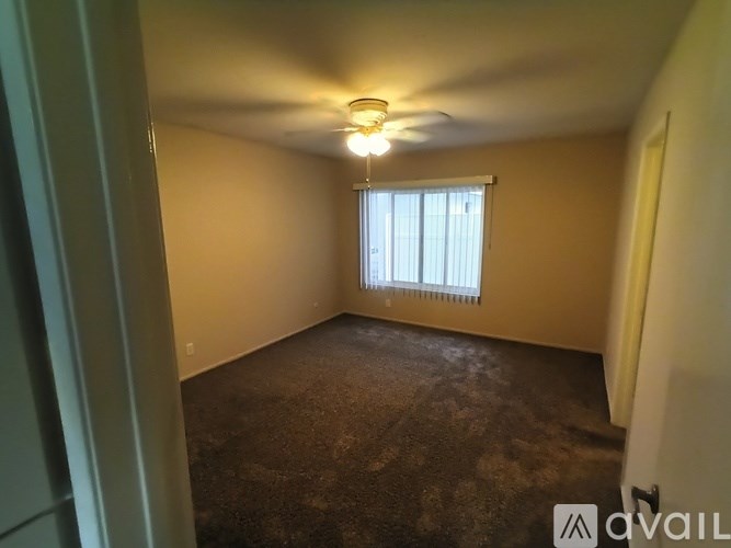 A room with a carpeted floor and a window with blinds.