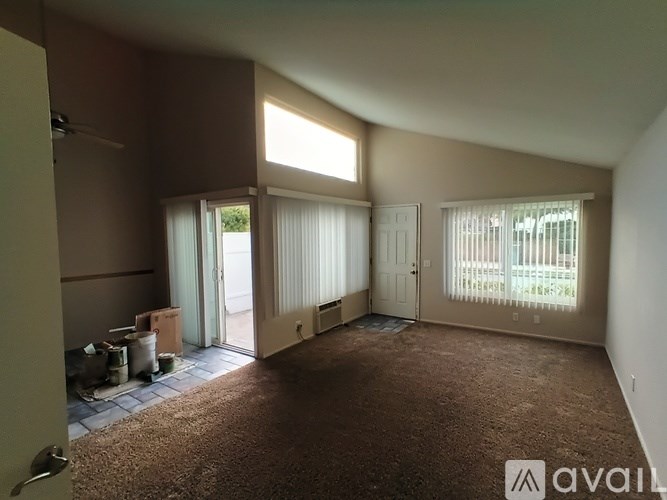 A room with brown carpet and a door leading outside.