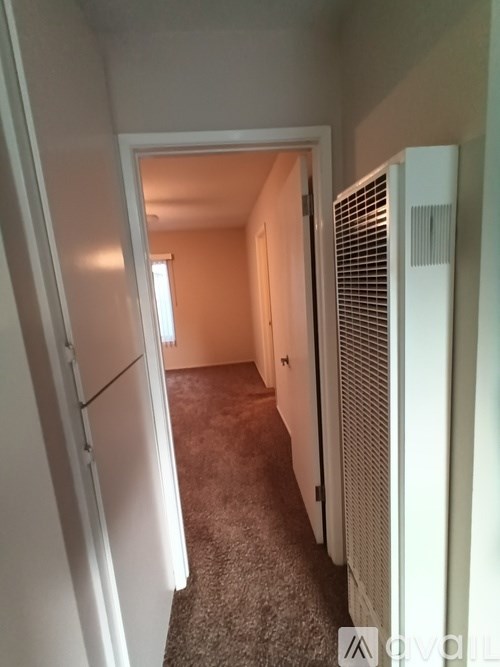 A hallway with a carpeted floor and a white door.