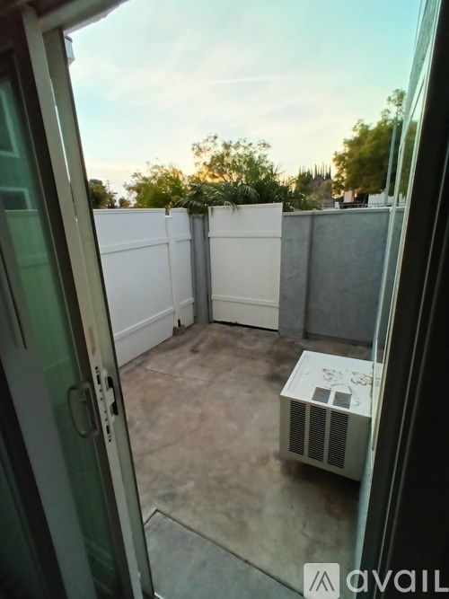 A patio with a white fence and an air conditioning unit.